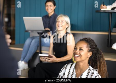 Group of diverse professionals engaging in discussion with standing presenter Stock Photo