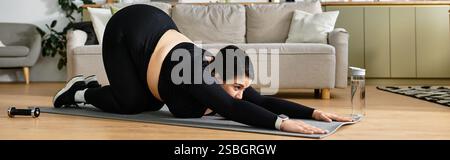 Practicing yoga poses in a comfortable living space, focused on physical wellness and relaxation. Stock Photo
