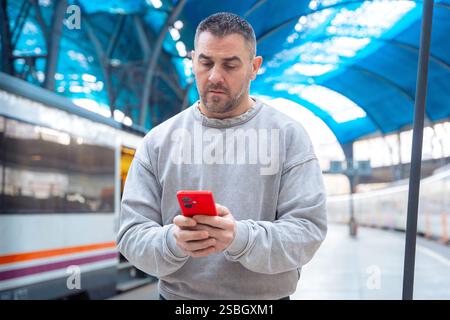 Man using smartphone at train station while traveling Stock Photo