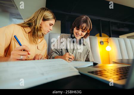 Teenage students working together on school homework, sharing ideas in a contemporary study environment. Focused learning and collaboration are key th Stock Photo