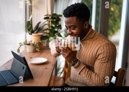 Young man using digital tablet to communicate online. He is sitting in bar,drinking tea and having video call. Stock Photo