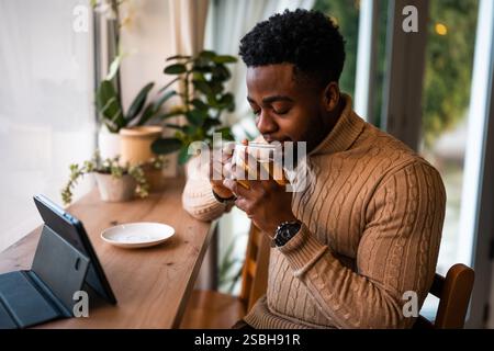 Young man using digital tablet to communicate online. He is sitting in bar,drinking tea and having video call. Stock Photo