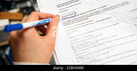 A hand holding a blue pen marks a section titled Innere Organe translated as internal organs on a printed medical questionnaire, indicating a detailed Stock Photo