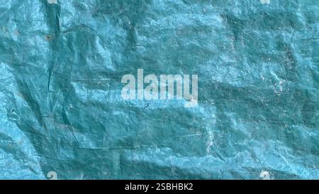 A close-up view of a textured blue tarp with visible creases and color variations under natural light. Stock Photo