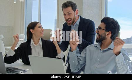Happy creative team celebrate victory in office successful sales stock market data online business people businessmen and businesswoman winning Stock Photo