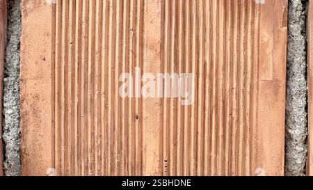 This weathered clay wall features a fascinating texture and unique patterns under soft sunlight. Stock Photo