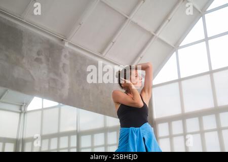 Portrait of woman practices ballet and rehearses in studio with large windows Stock Photo