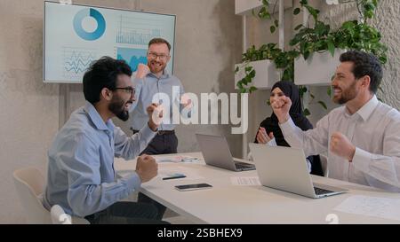 Happy team colleagues celebrate winning business deal achieve victory give high five multiethnic businessmen and muslim businesswoman in hijab working Stock Photo