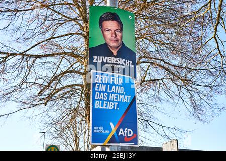Essenbach, Bavaria, Germany - February 1, 2025: Two election posters for the 2025 federal election on a lamp post: At the top a poster from Bündnis 90/Die Grünen with Robert Habeck and the slogan: Zuversicht. Below it, an AfD poster with: Time for a country that remains home *** Zwei Wahlplakate zur Bundestagswahl 2025 an einem Laternenmast: Oben ein Plakat von Bündnis 90/Die Grünen mit Robert Habeck und dem Slogan: Zuversicht. Darunter ein AfD-Plakat mit: Zeit für ein Land, das Heimat bleibt Stock Photo