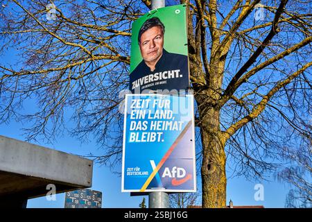 Essenbach, Bavaria, Germany - February 1, 2025: Two election posters for the 2025 federal election on a lamp post: At the top a poster from Bündnis 90/Die Grünen with Robert Habeck and the slogan: Zuversicht. Below it, an AfD poster with: Time for a country that remains home *** Zwei Wahlplakate zur Bundestagswahl 2025 an einem Laternenmast: Oben ein Plakat von Bündnis 90/Die Grünen mit Robert Habeck und dem Slogan: Zuversicht. Darunter ein AfD-Plakat mit: Zeit für ein Land, das Heimat bleibt Stock Photo