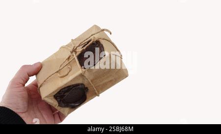 Hand holding a small gift box wrapped on white background. theme of gifts, holidays. Delivery Service Concept. Stock Photo