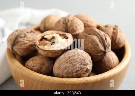 Fresh walnuts in bowl on gray table, closeup Stock Photo