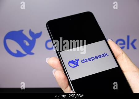 DeepSeek Ai logo on smartphone screen in a female hand and computer display Stock Photo