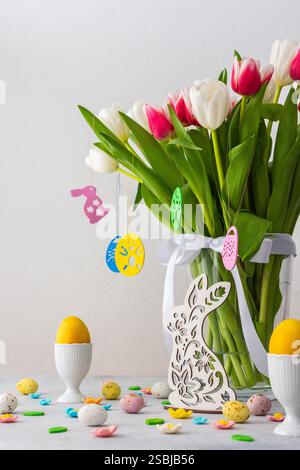 Happy Easter concept, beautiful spring bouquet of pink and white tulips and bunny looking for Easter eggs Stock Photo