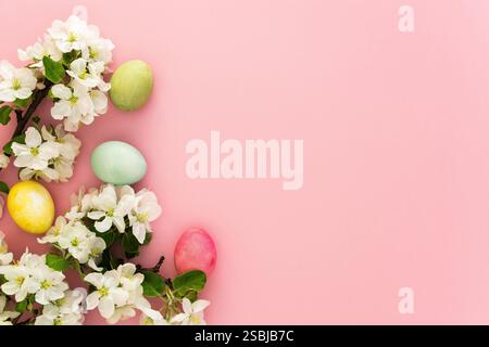 Spring Easter background, multi-colored Easter eggs and blooming apple tree branches on a pink background Stock Photo