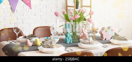 Beautiful table setting for Easter dinner with fresh flowers and bunnies at home Stock Photo