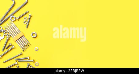 Tap bolts, nuts and screwdriver bits on yellow background with space for text Stock Photo