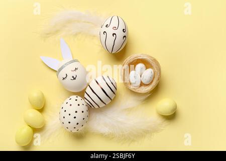 Composition with different creative Easter eggs and feathers on beige background Stock Photo