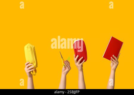 Female hands with pencil cases, notebook, scissors and ruler on yellow background Stock Photo