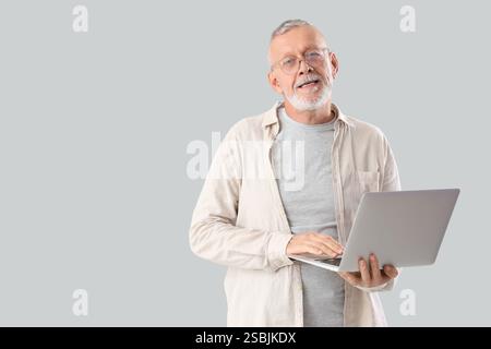 Mature programmer working with laptop on light background Stock Photo