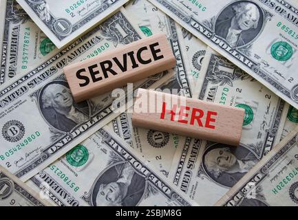 Service here symbol. Concept words Service here on wooden blocks. Beautiful dollar background. Business and Service here concept. Copy space. Stock Photo