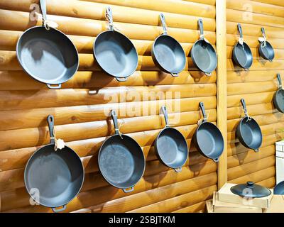 Frying pans on a wooden wall in a store Stock Photo