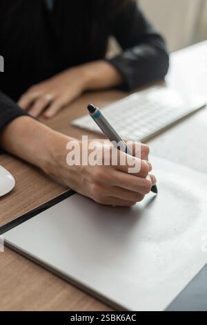 An office woman using a stylus on a drawing tablet, focused on her work. Perfect for business, digital art, and technology content. Ideal for projects Stock Photo