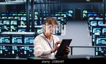Competent manager in server hub housing high end devices capable of quickly and efficiently performing complex computations and data analysis, using tablet to end concerns Stock Photo