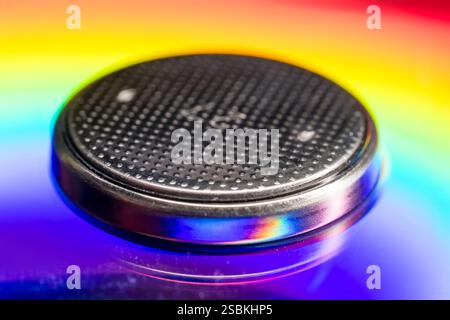 Extreme close up view of Button battery on a colorful disc background. Stock Photo