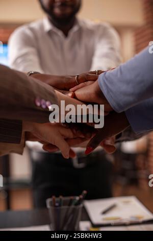 Multiethnic employees stack hands in startup office, representing collaboration, inclusion, and equality. The gesture signifies great teamwork and partnership at group business meeting. Stock Photo