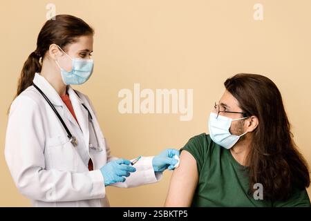 Female doctor making vaccination for long-haired indian guy Stock Photo