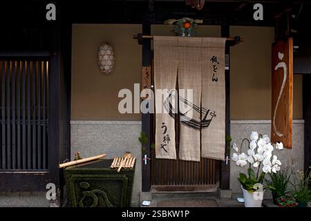 Upscale Uokeya U unagi (eel dishes) traditional Japanese restaurant on backstreet in Gion with noren, flowers, sign and water basin at entry, Kyoto. Stock Photo