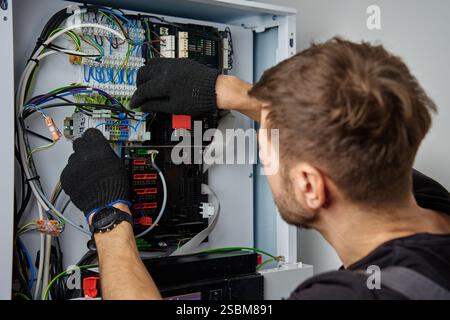 Technician working on internal wiring of heat pump, inspecting electrical connections. Specialist servicing heating and cooling system. Electrician wi Stock Photo