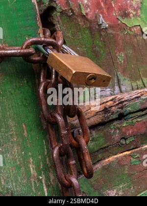 Padlock closes the wooden gate with a rusty chain, in Brazil Stock Photo