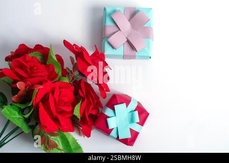 Elegant bouquet of red roses with two beautifully wrapped gift boxes, symbolizing love, joy, and celebration against a white background. Stock Photo