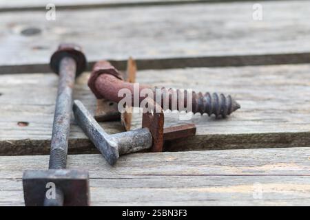 several metal hooks and screws placed on the wooden surface. Stock Photo