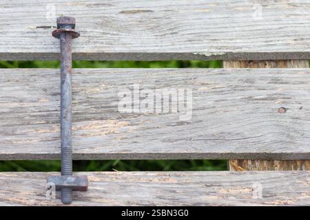 a long metal screw with a nut and washer on a wooden surface. Stock Photo