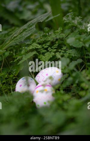 Three colorful hand-painted easter eggs nestled in lush green grass create a joyful springtime scene Stock Photo