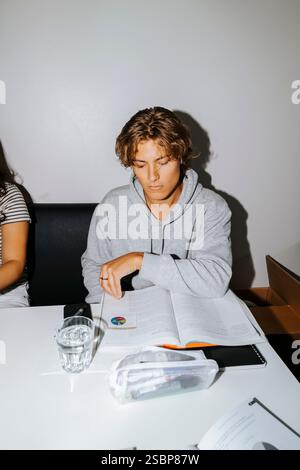 Young man studying while sitting at desk in college dorm Stock Photo