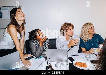 Happy male and female students laughing while studying in college dorm room Stock Photo