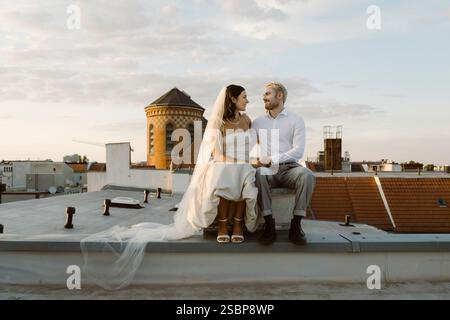 Young male and female married couple sitting together on rooftop Stock Photo