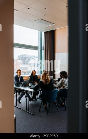 Male and female business professionals discussing strategies in team meeting at office Stock Photo