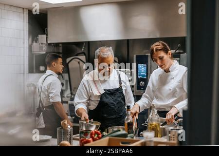 Female and male chef wearing uniform cooking food in kitchen at restaurant Stock Photo