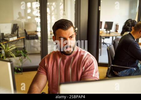 Focused male computer programmer working in tech startup office Stock Photo