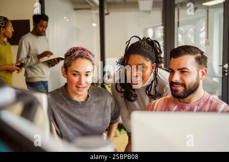Multiracial male and female computer programmers discussing with each other in tech office Stock Photo