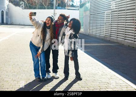 Three cheerful young friends are taking a selfie together outdoors on a bright winter day, enjoying their time together Stock Photo