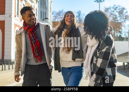 Group of young students enjoying a sunny winter day in the city center, wearing warm clothes and laughing together Stock Photo