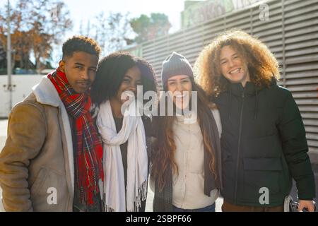 Four cheerful multi ethnic young students are posing together for a group photo outside on a sunny winter day Stock Photo