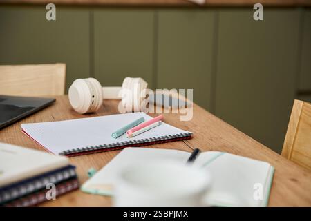 Colourful pens with notebooks and headphones on table in well lit room. Stock Photo