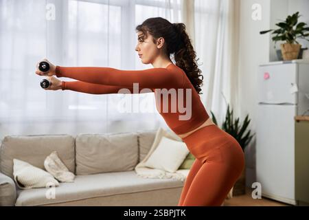 Focused and dedicated, a beautiful young woman engages in a fitness routine at home. Stock Photo
